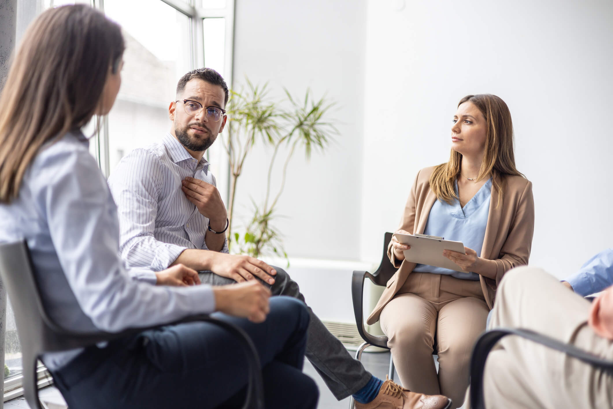 Adult man speaking to the group in a therapy session held in a modern office environment