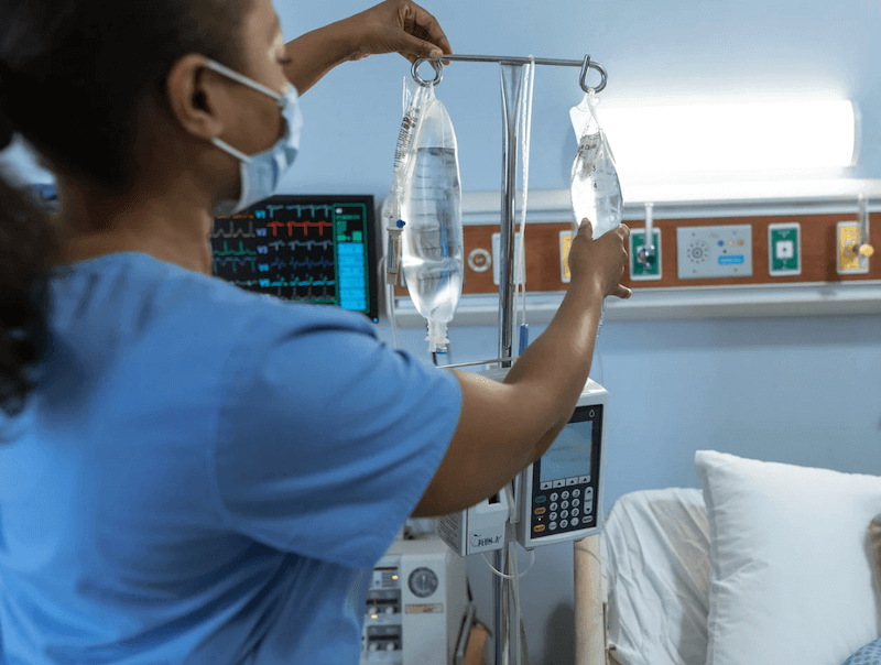 Nurse in mask checking patient drip